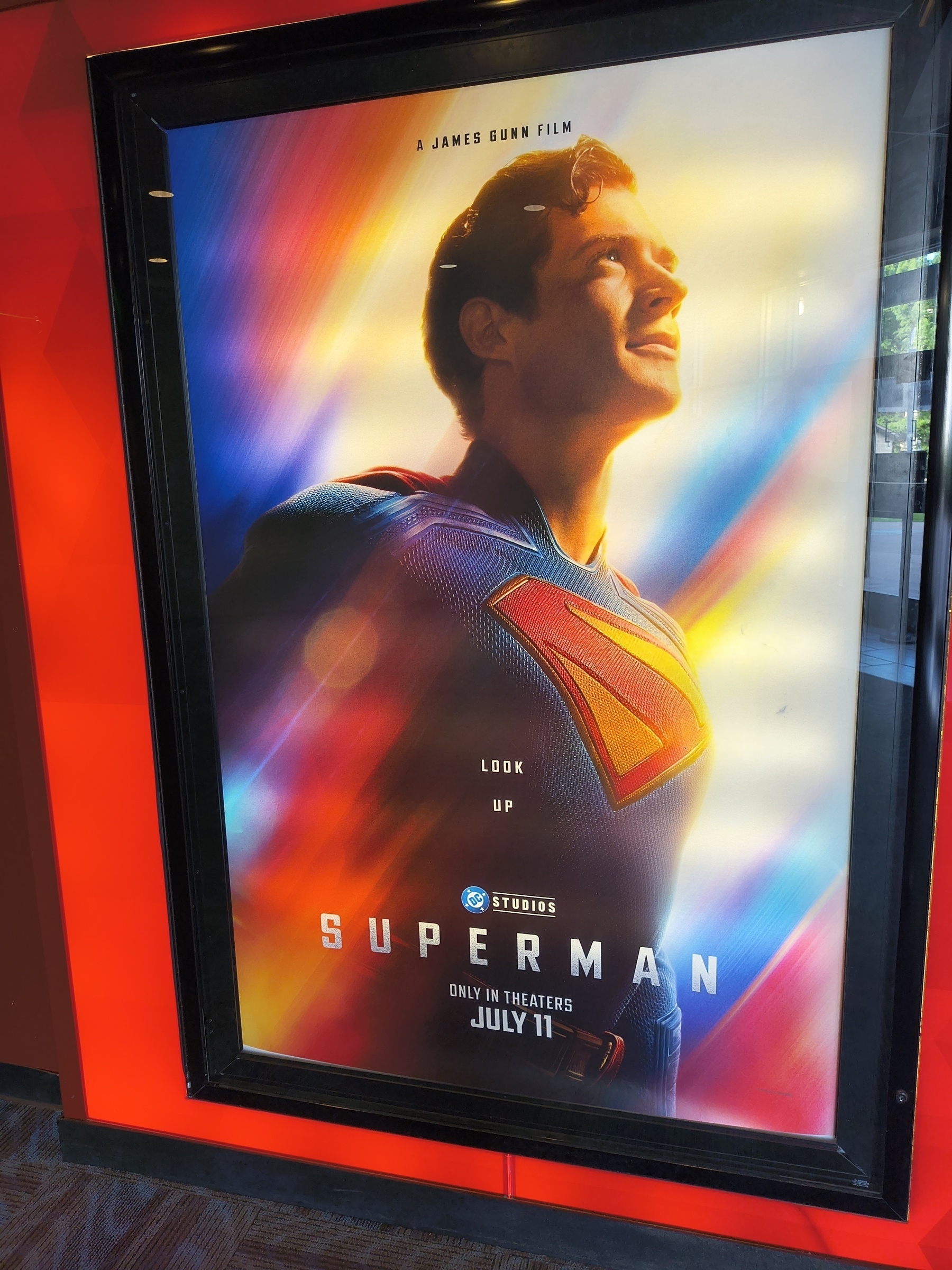 Auto-generated description: A vibrant movie poster features a superhero in a colorful suit looking upwards, with the text Superman and a release date of July 11.