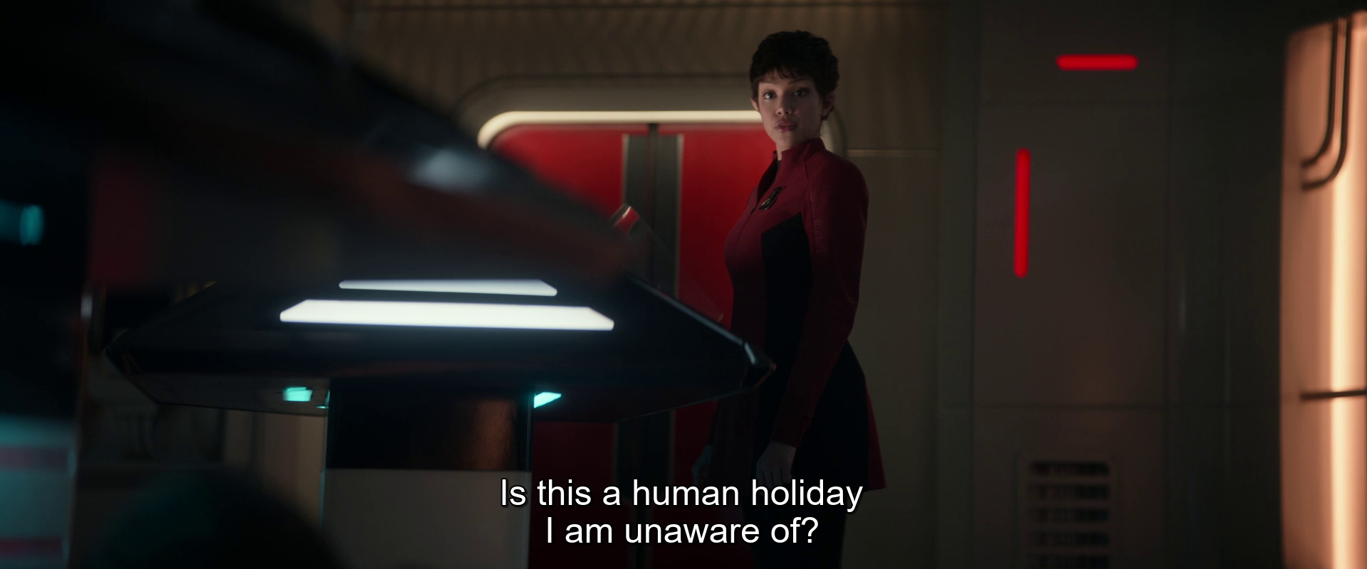 A person in a futuristic setting is looking towards a table and asking, Is this a human holiday I am unaware of?