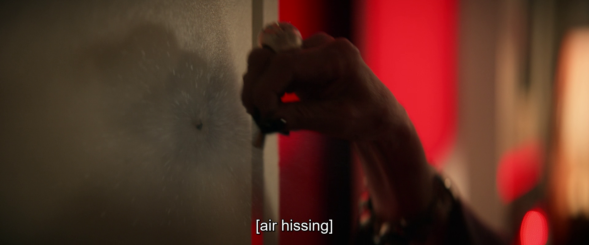 A hand is shown pressing a small object against a surface, accompanied by the subtitle [air hissing].